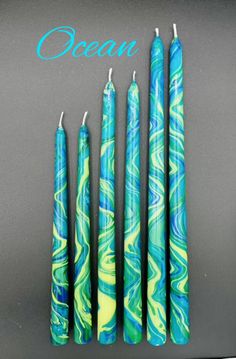 four blue and green candles sitting next to each other