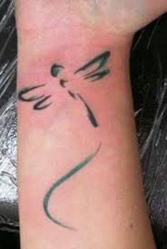 a woman's arm with a dragonfly tattoo on the left side of her wrist