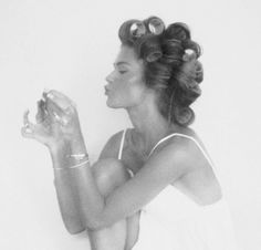 a black and white photo of a woman with her hair in curls holding something