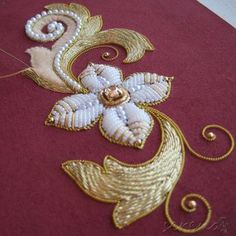 a close up of a piece of cloth with gold thread and beads on top of it