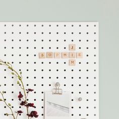 a white pegboard with some flowers and letters on it