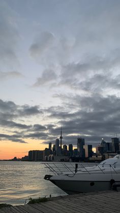 two boats are docked in the water next to a large cityscape at sunset