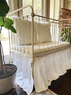 a white bed sitting next to a potted plant on top of a hard wood floor