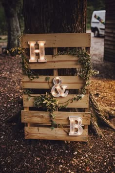 a wooden sign with lights on it that says h and b next to a tree