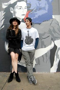 a man and woman standing in front of a mural