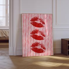 a painting with red lipstick drawn on it in front of a white wall and wooden floor