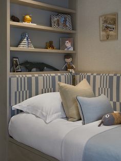 a bed with pillows and stuffed animals on top of it in a room filled with shelves