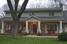 a house with porches and lights on the front door is surrounded by green grass