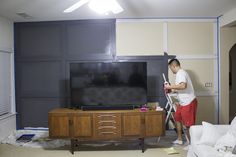 a man standing in front of a flat screen tv on top of a wooden entertainment center