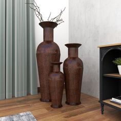 three brown vases sitting next to each other on a wooden floor