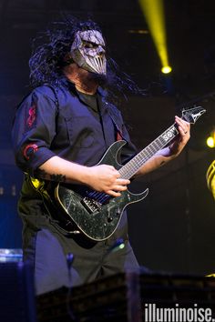 a man with long hair playing an electric guitar