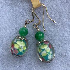 Offering A Brand New, One Of A Kind, Handmade Pair Of Drop Earrings Comprised Of A Floral “Lamp-Work Bead” In Green, Pink, White & Yellow. It’s Topped With A 4mm Green Jade Bead & Hangs 1.75” Long On Sterling Silver Ear-Wires. Cute! Bead Earrings, Floral Lamp, Lampwork Bead Earrings, Themed Jewelry, Jade Beads, Green Jade, Beaded Jewelry Diy, Jade Green, Jewelry Diy