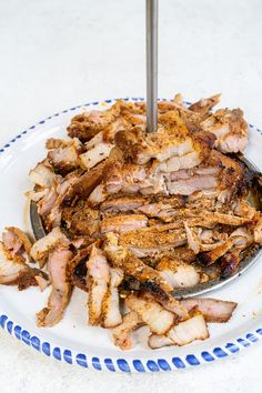 a white plate topped with sliced meat on top of a blue and white tablecloth