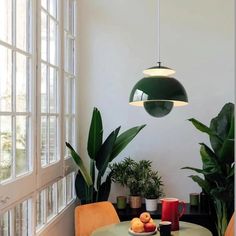 a dining room table with green chairs and potted plants