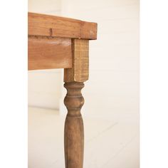 an old wooden bench with wood slats on the top and bottom edge, in front of a white wall