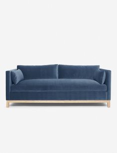 a blue velvet couch with wooden legs on a white background, it's all in the shape of a sofa