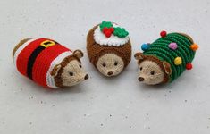 three knitted hedges with christmas decorations on them, one wearing a santa hat