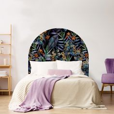 a bed with a floral headboard and purple chair next to it in a white room