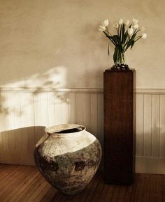 a vase with flowers in it sitting next to a tall wooden box on the floor