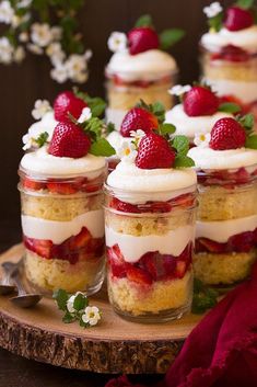 strawberry shortcakes with whipped cream and fresh strawberries in small jars on a wooden tray