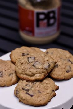 chocolate chip cookies on a white plate with peanut butter in the backgrouf