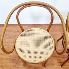 two wooden chairs sitting next to each other on top of a hard wood floored floor