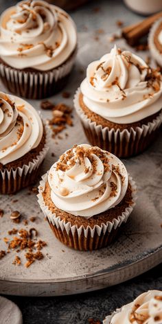 cupcakes with white frosting and cinnamon sprinkles on a tray