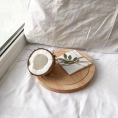 a wooden tray with a coconut on it next to a book and window sill