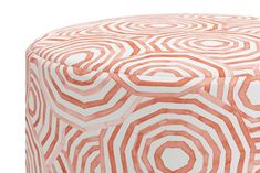 an orange and white ottoman with circular designs on the top, sitting in front of a white background