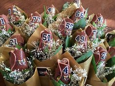 a bunch of flowers with numbers on them sitting in brown paper wrapped bags next to a wooden table