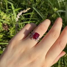 a woman's hand with a ring on it and a red stone in the middle