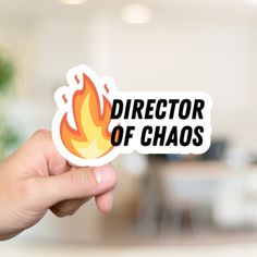 a person holding up a sticker that says director of chaos