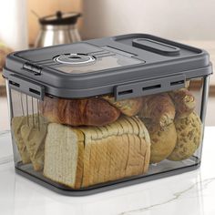 a plastic container filled with bread and croissants on top of a counter