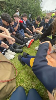 a group of young people sitting on top of a grass covered field next to each other