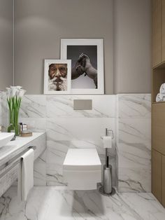 a white toilet sitting next to a bathroom sink under a framed picture on the wall