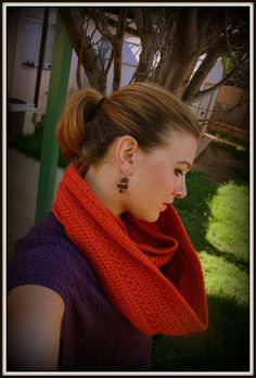 a woman wearing a red scarf and earring in front of a tree with green grass