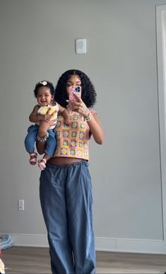 a woman taking a selfie while holding a baby in front of her and an adult standing behind her