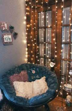 a blue chair sitting in front of a window with lights on the wall behind it