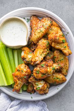 chicken wings with celery and ranch dressing in a white bowl on a gray surface