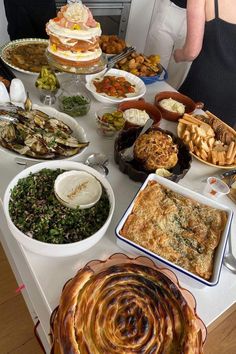 a table filled with lots of food on top of a white table covered in dishes