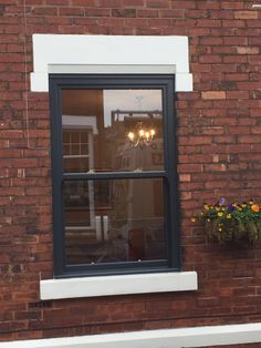 a brick building with a window and potted plants in the window sill next to it