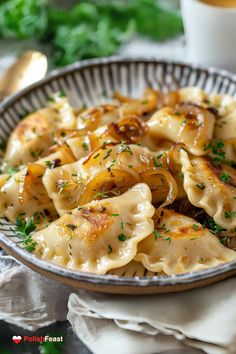 a bowl filled with pasta and onions on top of a white table cloth next to a cup of coffee