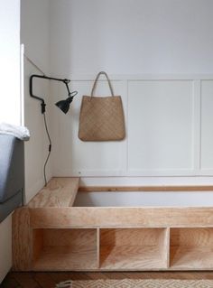 a wooden bench sitting next to a wall with a basket hanging on it's side