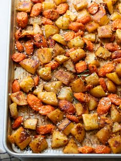 roasted potatoes and carrots in a baking pan with parmesan cheese on top