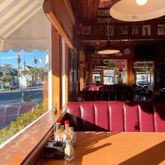 the inside of a restaurant with red booths and white awnings on the windows