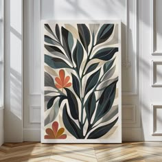 an art print with leaves on it in a white frame next to a wooden floor