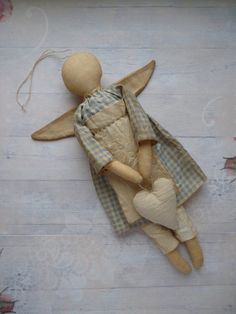 a wooden doll laying on top of a white floor next to a string and heart