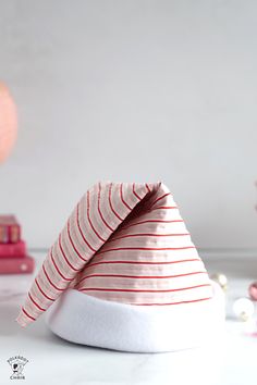 a red and white striped hat sitting on top of a table next to some books