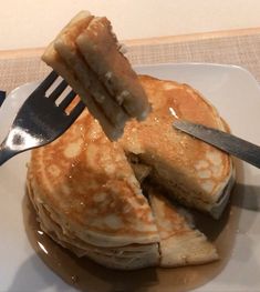 a stack of pancakes being cut with a knife and fork