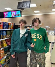 two young men standing next to each other in front of a grocery store display case